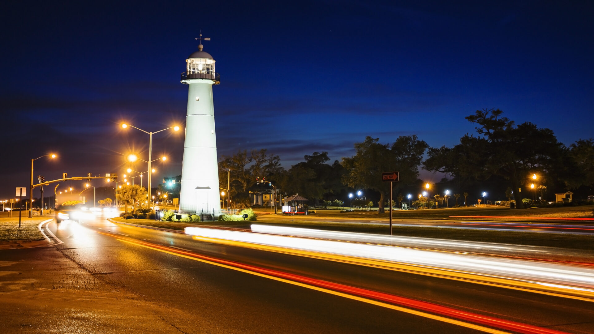 Lighthouse at night with car light trails